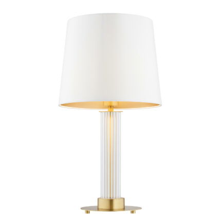 Glass table lamp with cream fabric shade and light bulb on.
