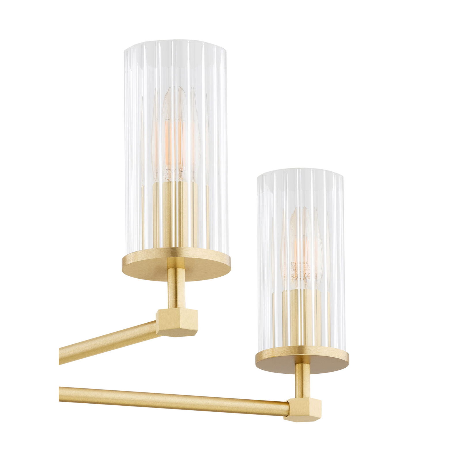 Two brushed brass arms of Ampton chandelier with clear ribbed glass cylindrical shades mounted.
