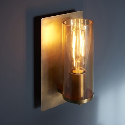 Zoomed in left side angle view of the Leo Wall Light in antique brass with tinted glass and one lamp.