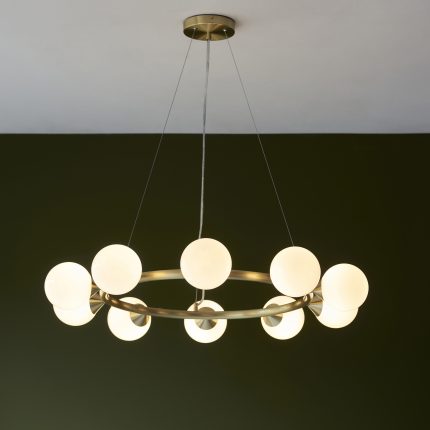 Full view of the Nexus Large Chandelier, 10 round glass lamps, brass finish, 91.7cm diameter, hanging against a green wall.