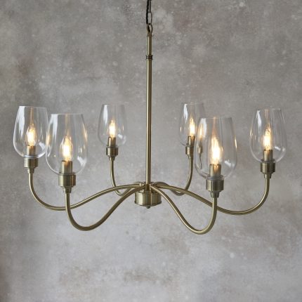 Zoomed in bottom half view of the Richmond Chandelier, 6 Light, antique brass and glass, hanging against a stone background.