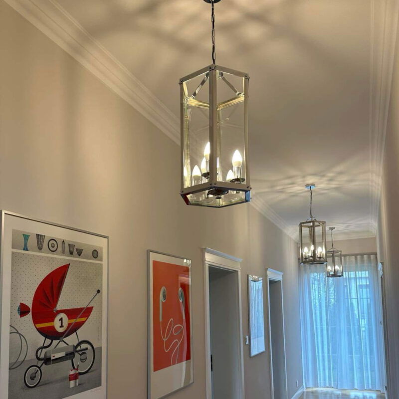 Chrome Borum lantern pendant light hanging in a hallway interior setting.