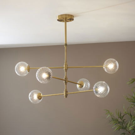 Deo Medium Pendant Lamp with six glass lights on brass frame hanging in room setting with eye level view.