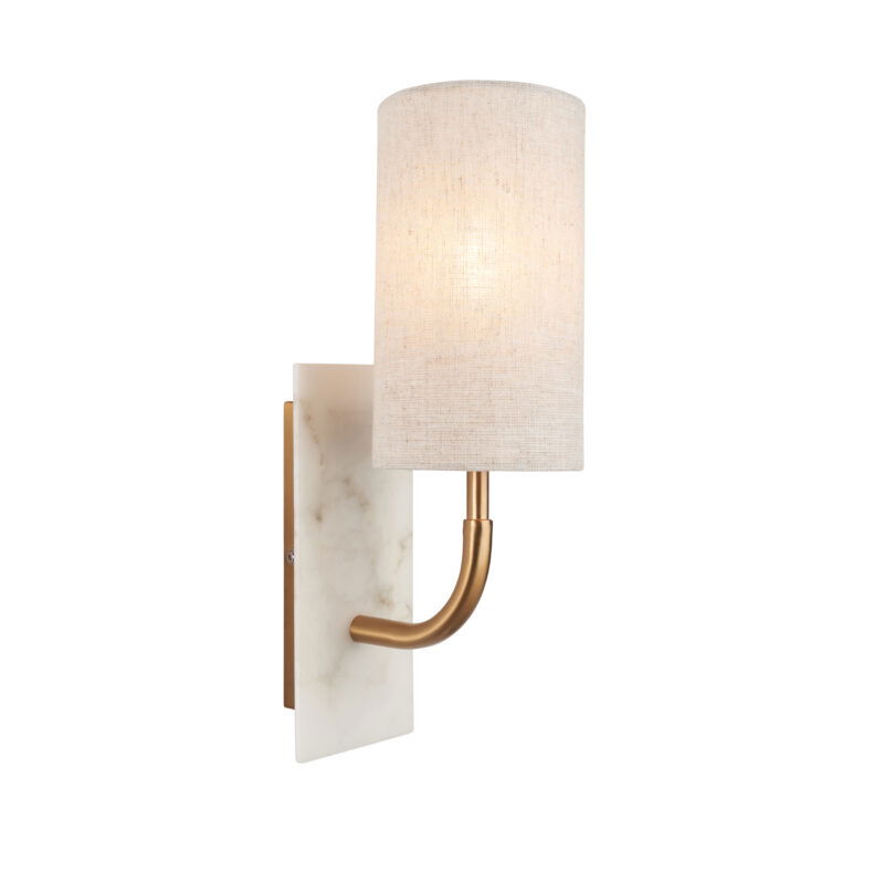 Side view of lit wall light with curved brass arm and glowing natural fabric shade extending from white marble mount against white background.