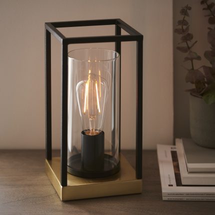 Zoomed in slight downward view towards the Habeo Table Lamp, black frame, brass base, clear glass.