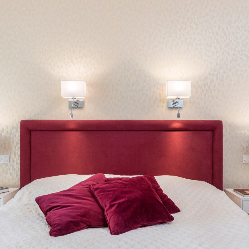 Two Laryi bedside wall light with white shade and adjustable LED reading light mounted on white wall.