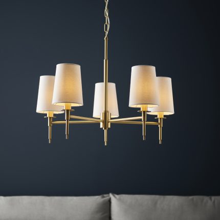 Zoomed-in front-facing view of the Lilt Chandelier in brass with 5 arms and white shades, 60cm in size, set against a contrasting navy blue wall.