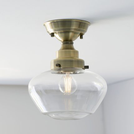 Close-up full product view of the Poro Semi-Flush Ceiling Lamp in antique brass with clear glass shade, measuring 25cm, installed on the ceiling.