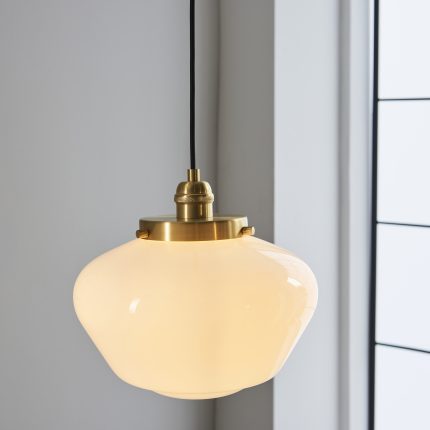 Eye level view, zoomed in, of the opal glass of the Poro Pendant Lamp, in warm white illumination, showing its brass and glass design.