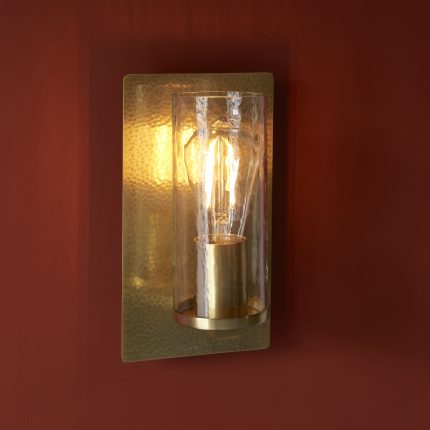 Side profile view of hammered brass wall light with clear glass panels against white background.